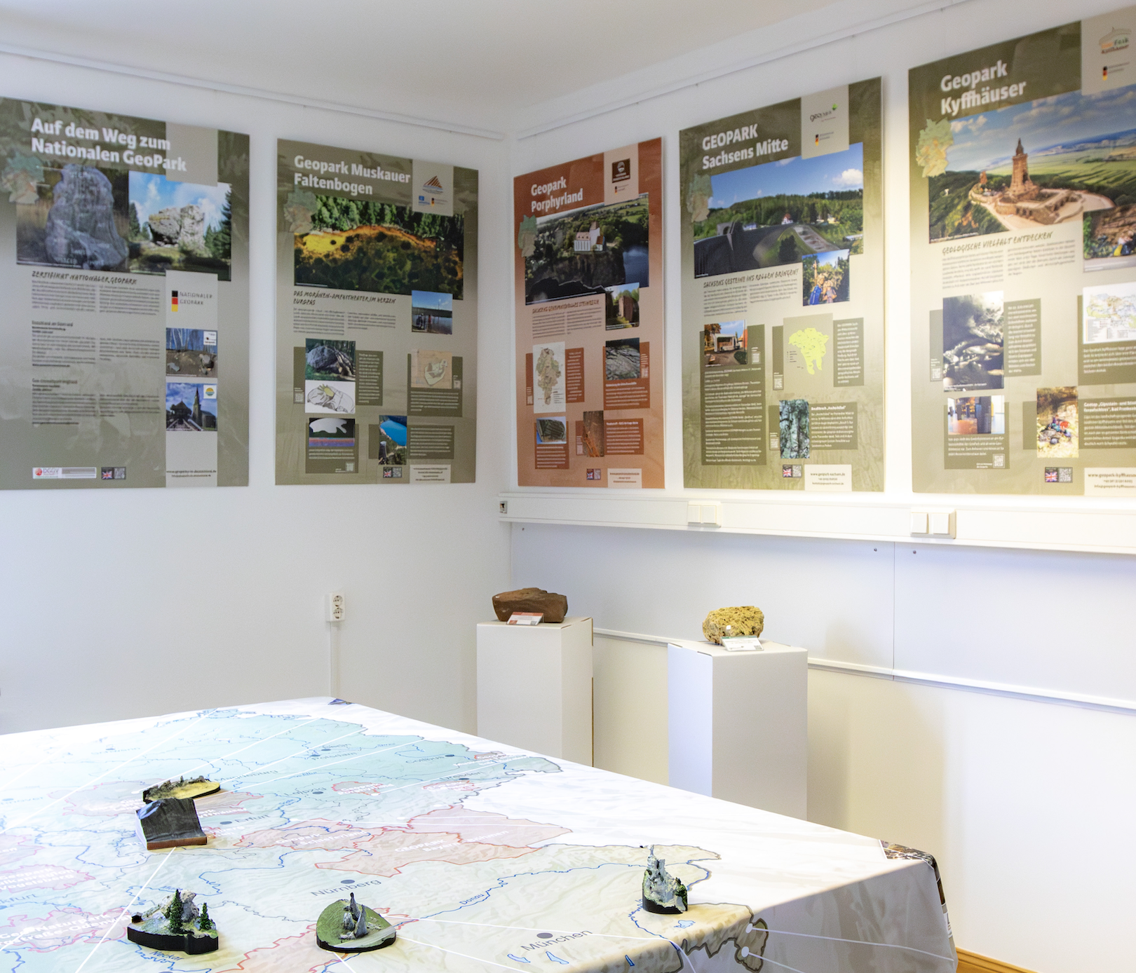 Ansicht der Ausstellung des Eiszeitmuseums. Man sieht im Hintergrund verschiedene Informationstafeln zu anderen Geoparks, im Vordergrund eine Karte, die sich über einen Tisch spannt.